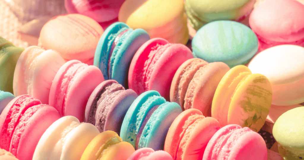 Colorful assortment of macarons in pastel pink, blue, yellow, green, and purple shades arranged in neat rows, creating a vibrant and appetizing display of the delicate French cookies—perfect for indulging your sweet tooth without a hint of food guilt.